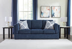Blue living room sofa set with three seat cushions and four patterned throw pillows