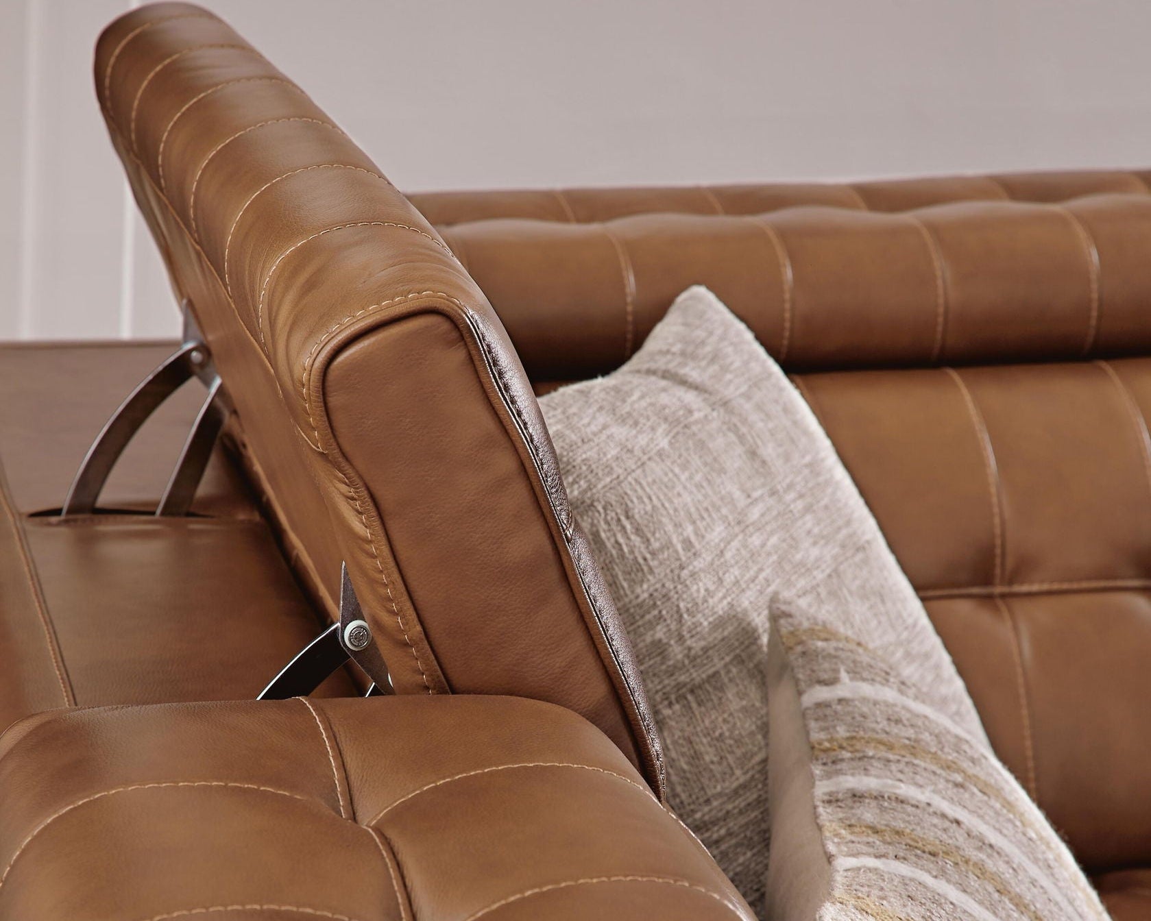 Brown reclining sectional sofa with curved arm and tufted cushions, plus throw pillow