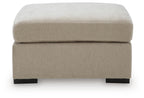 Oversized accent ottoman in light beige fabric with thick padded lid and dark block legs.