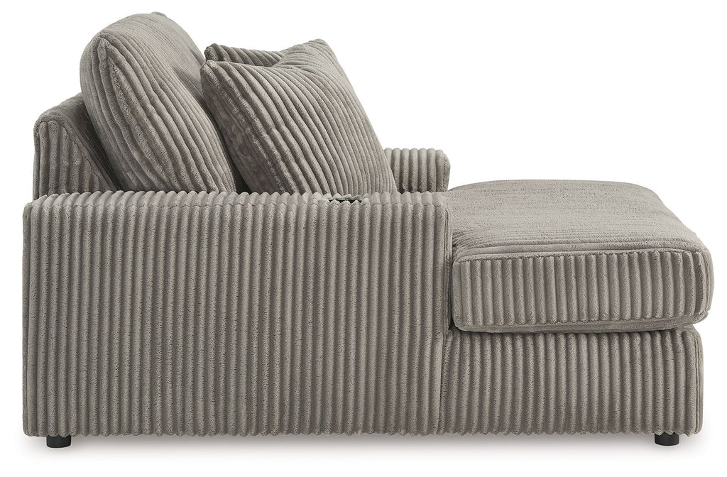 Corduroy chaise lounge chair in medium gray, side view with curved arm and pillows.