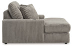 Corduroy chaise lounge chair in medium gray, side view with curved arm and pillows.