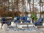 Outdoor lounge set with navy loveseat, multiple armchairs, and gray-framed table with glass top