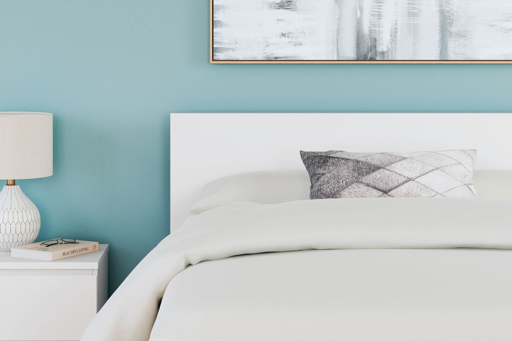 Light wood panel headboard with pillows on a bed.