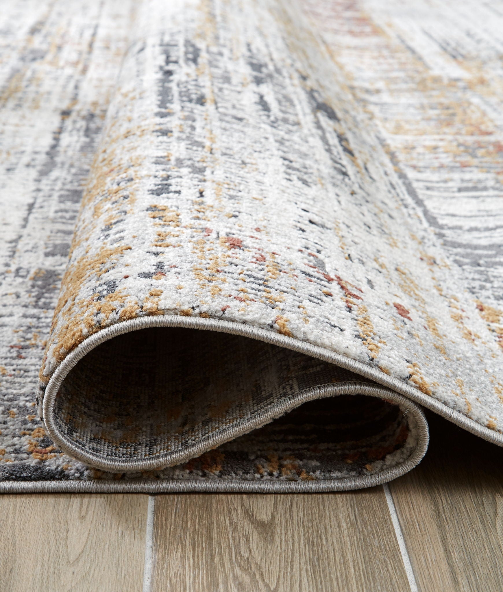 Abstract multi-color rug edge close-up with bound border, gray and white with orange