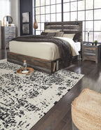 Rustic wood panel bed with white mattress and dark quilt, with matching dresser and nightstand