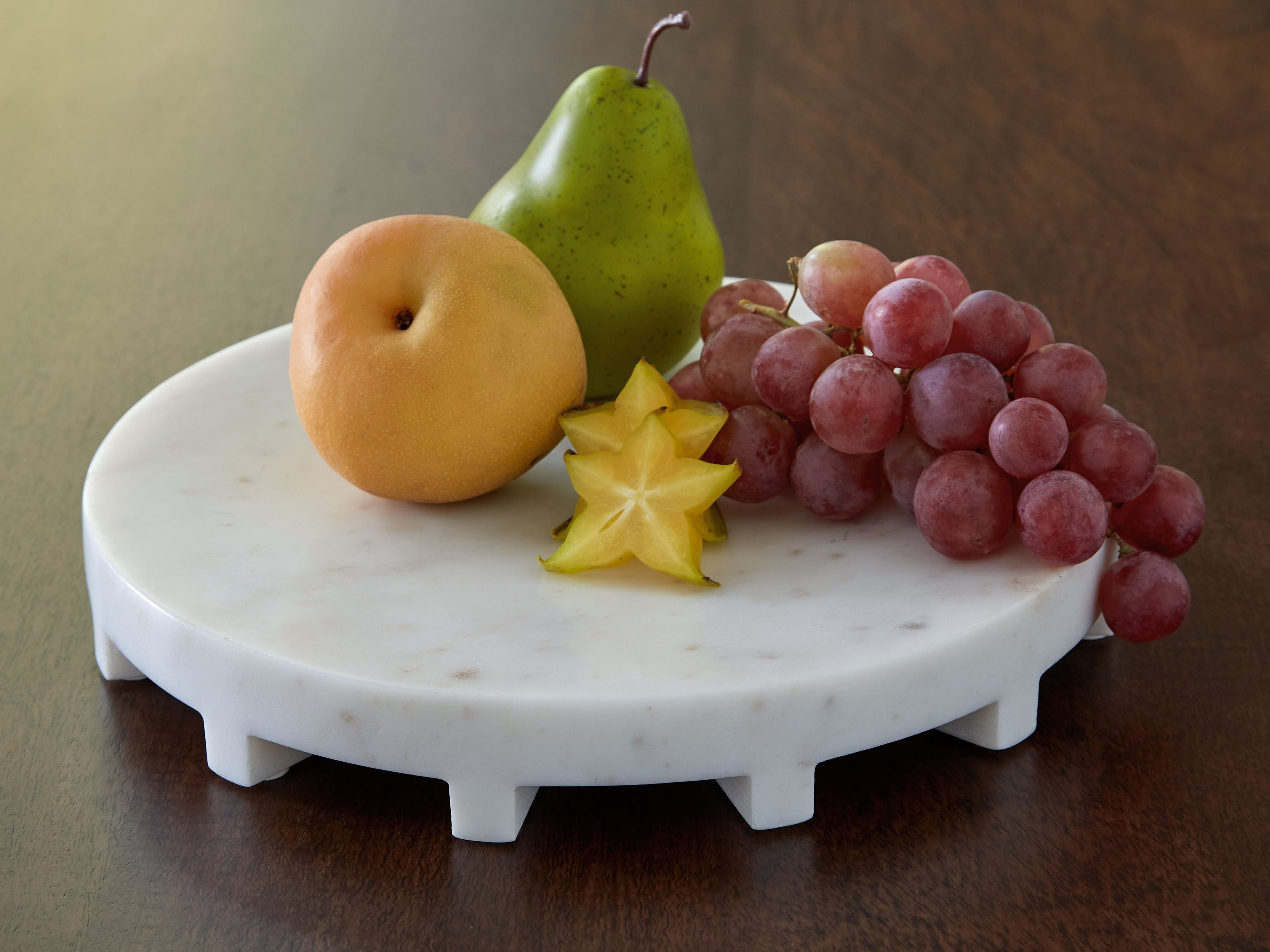 White round serving tray with pears, grapes, and star fruit