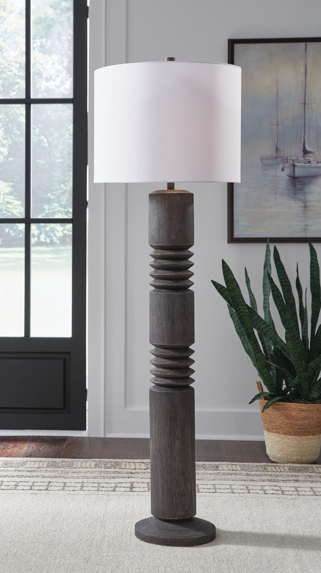 Distressed black floor lamp with white drum shade and stacked ribbed column body