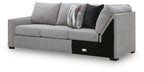 Grey sectional sofa with corner wedge, black base trim and patterned throw pillows on back