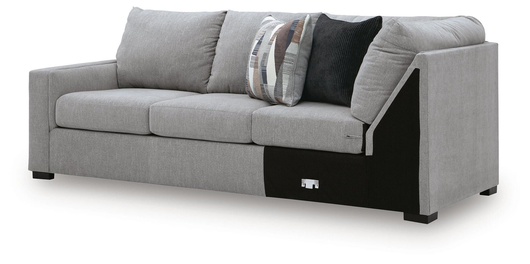 Grey sectional sofa with corner wedge, black base trim and patterned throw pillows on back