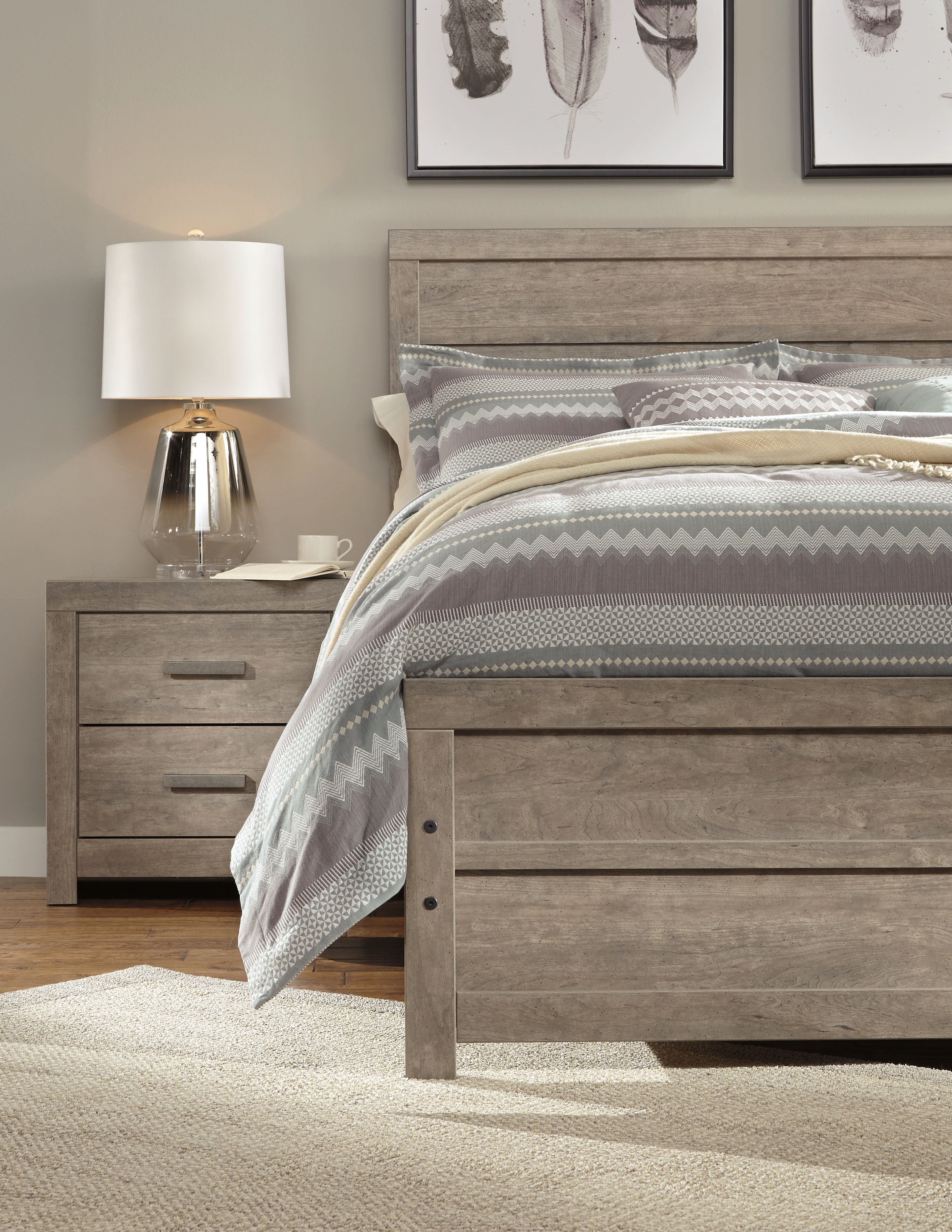 Gray panel nightstand beside bed with striped bedding and matching drawers