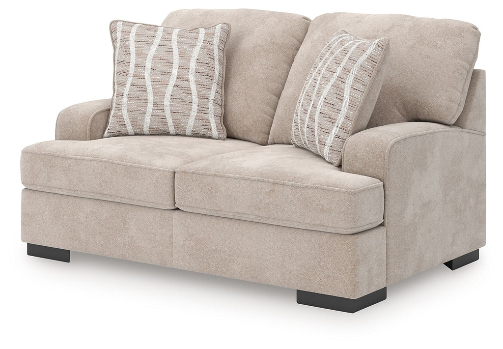Taupe loveseat with wide track arms, tufted seat cushions, and two gray striped pillows