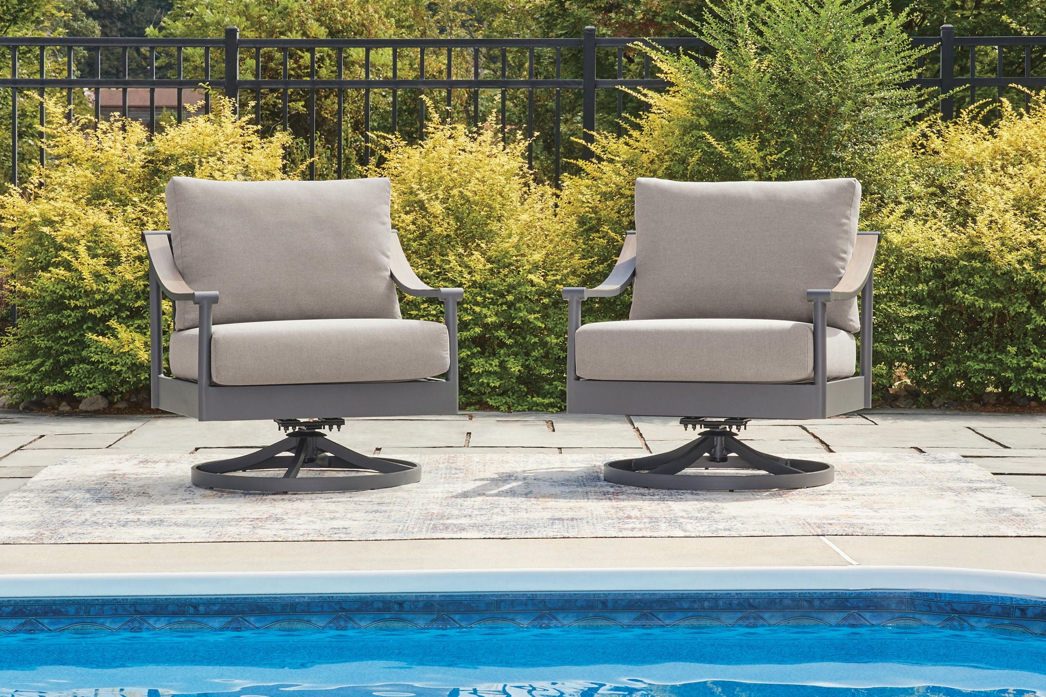 Set of two gray swivel lounge chairs with padded cushions and armrests