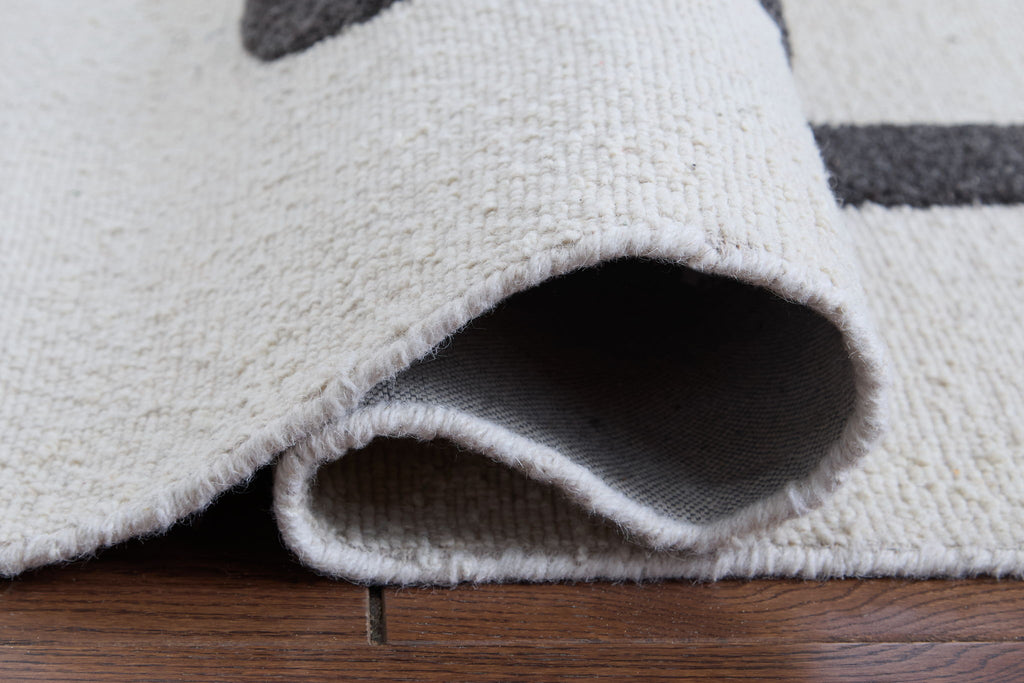Beige rug corner with rolled edge and visible backing