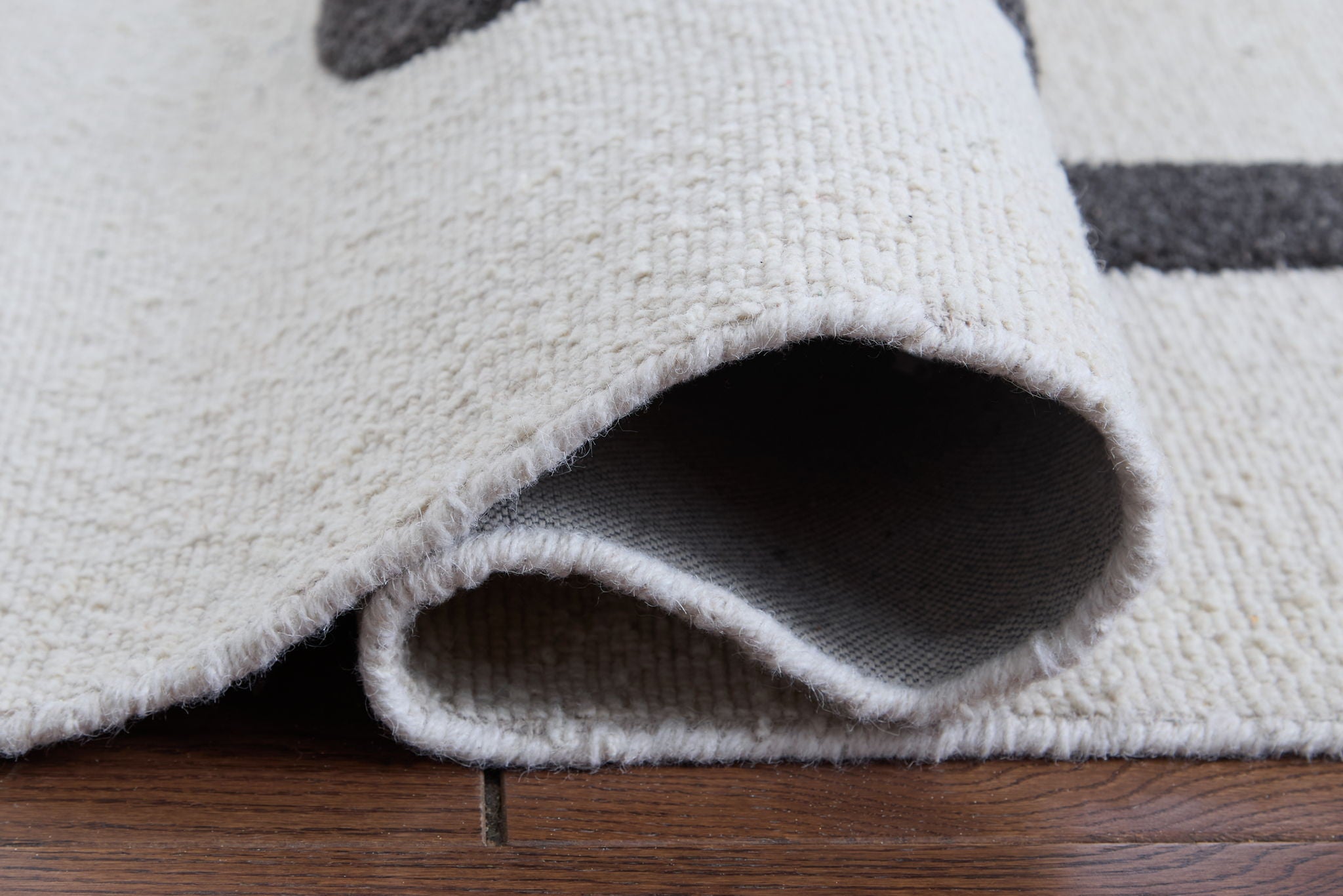 Beige rug corner with rolled edge and visible backing