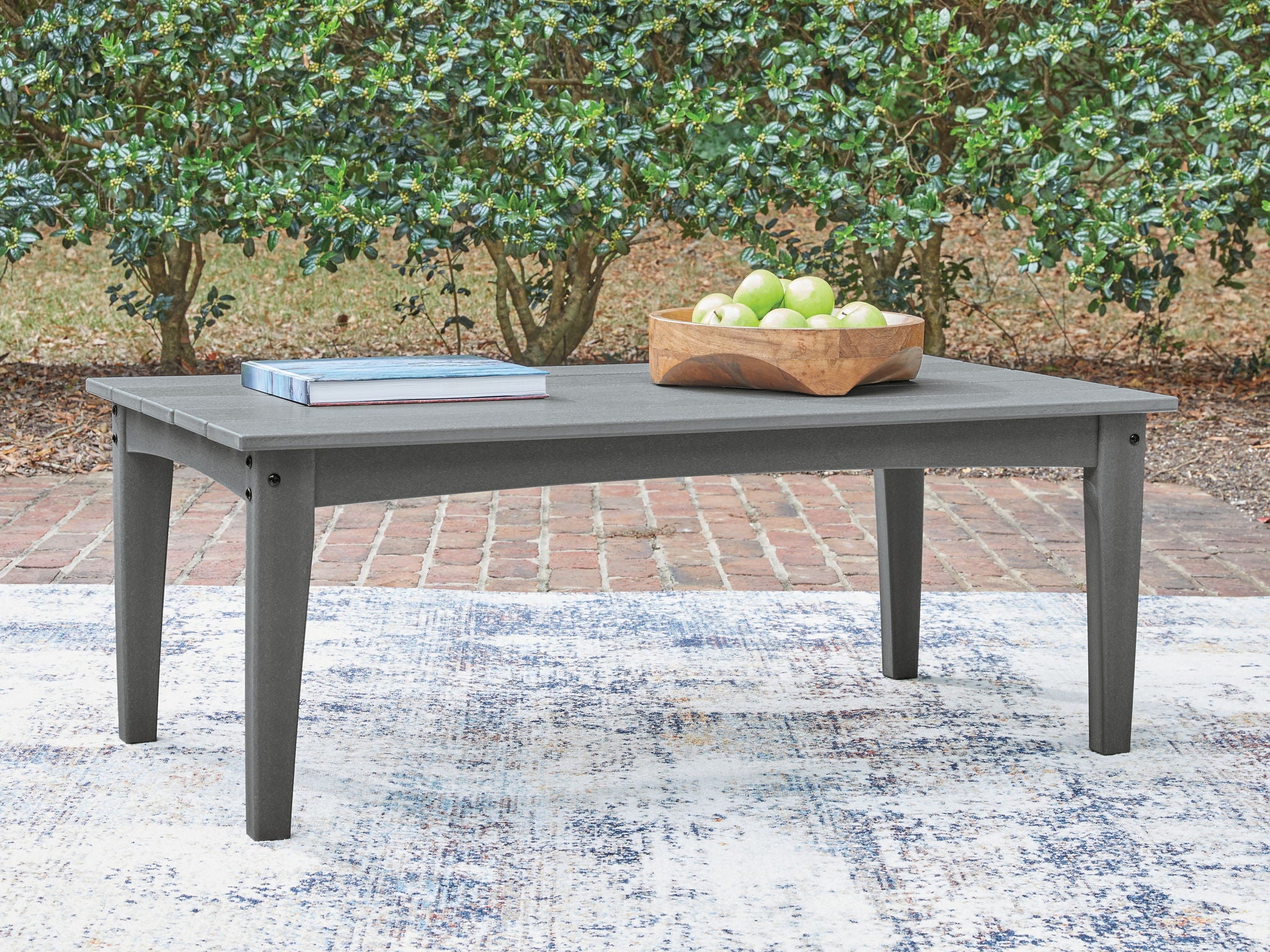 Gray outdoor cocktail table with slatted top, holding a fruit tray