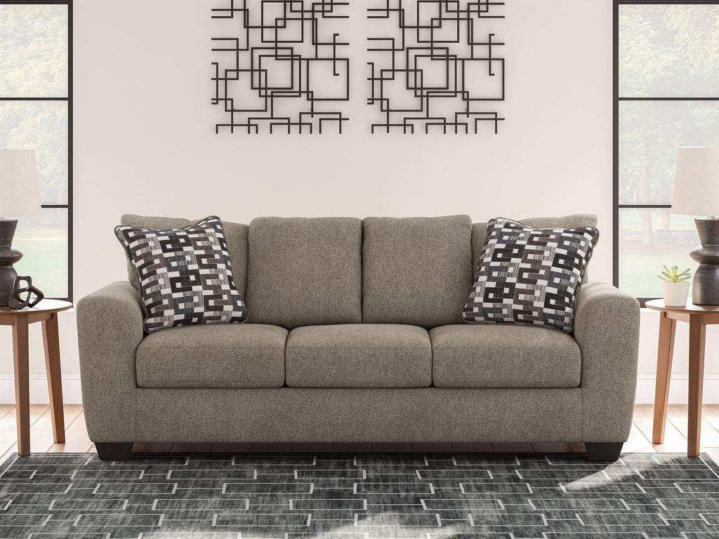 Gray suede sofa with back cushions and two black-and-white geometric pillows