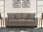 Gray suede sofa with back cushions and two black-and-white geometric pillows
