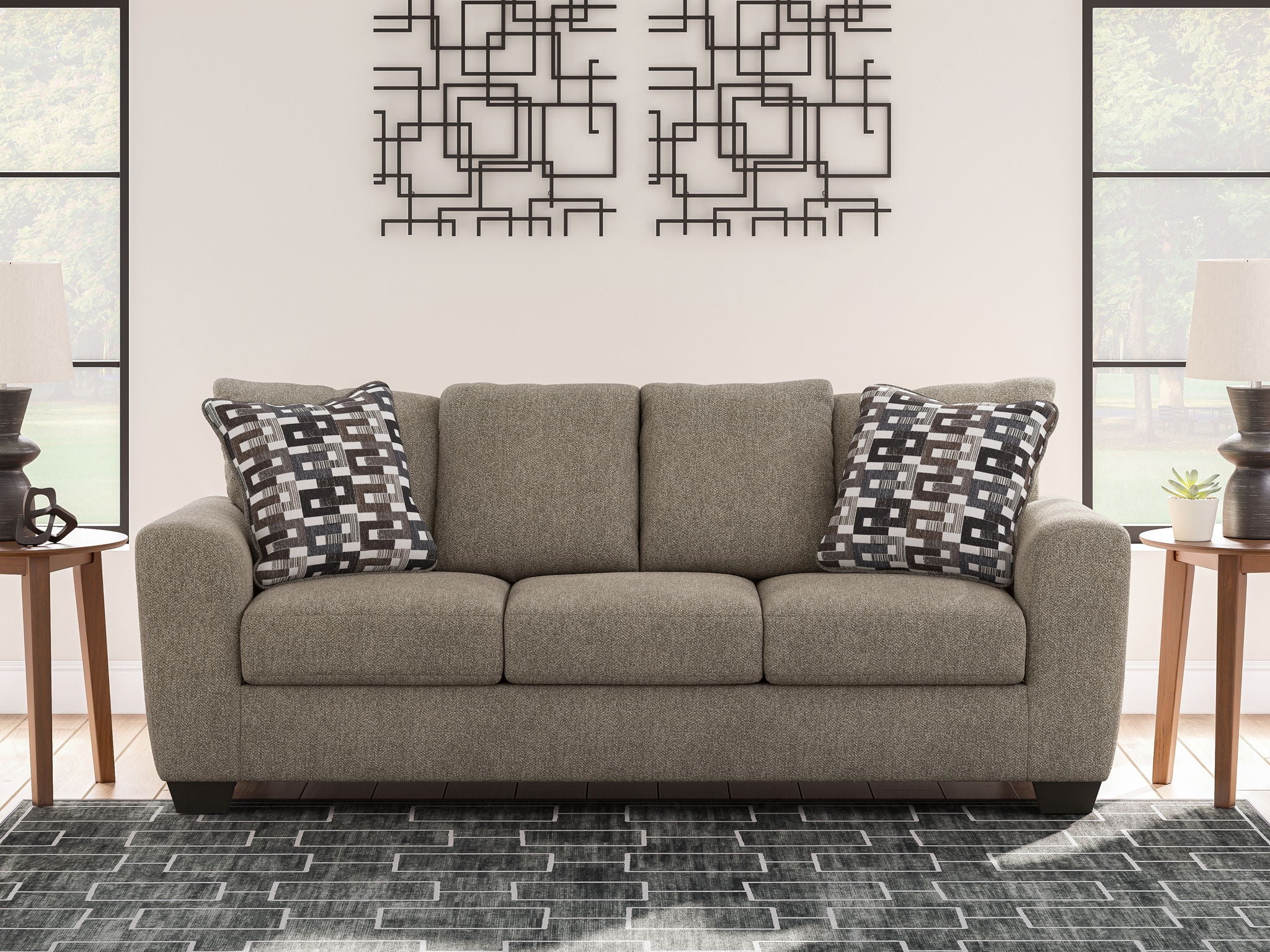 Gray suede sofa with back cushions and two black-and-white geometric pillows