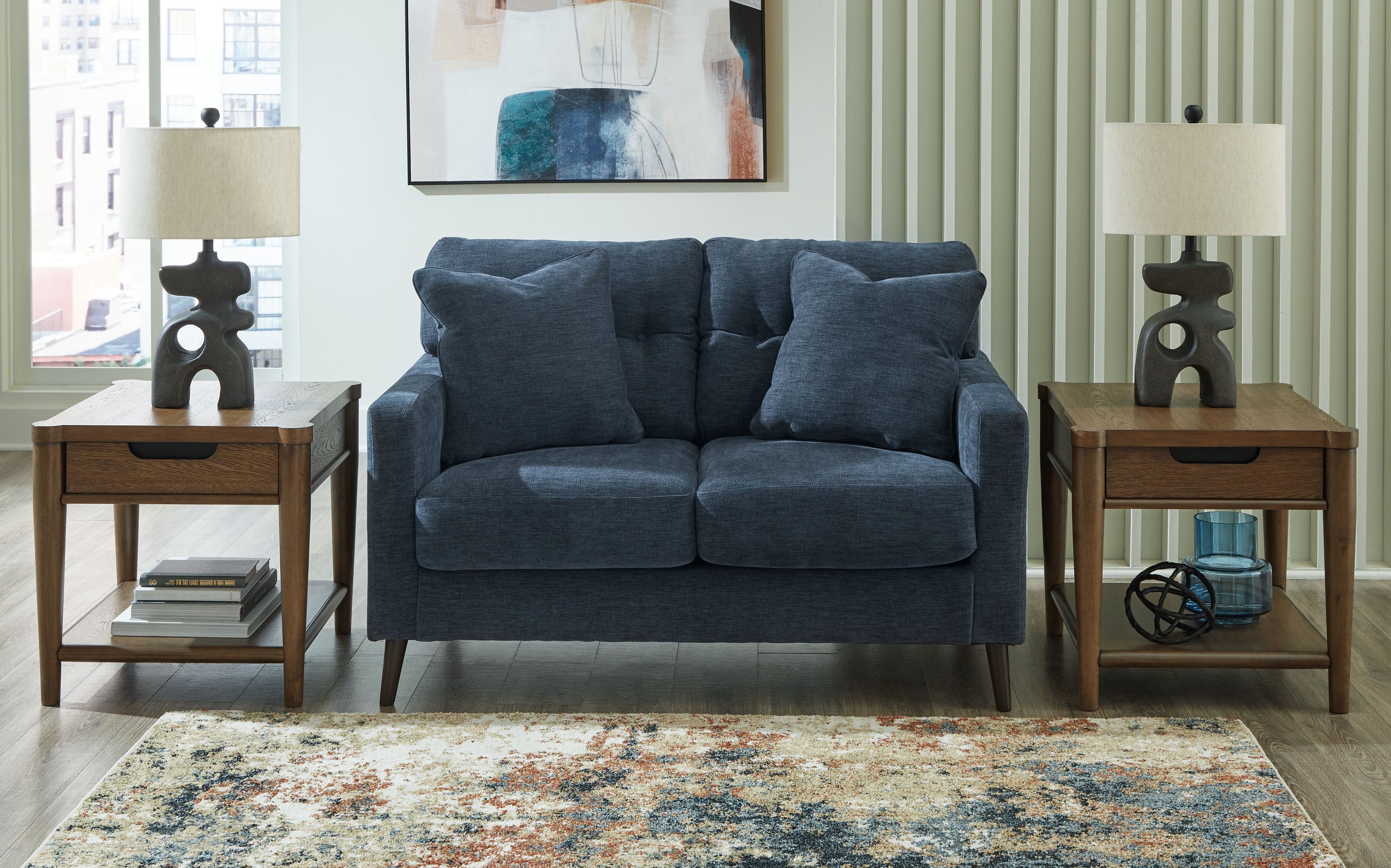 Blue loveseat with tufted back, rolled arms, and two seat cushions in a living room.
