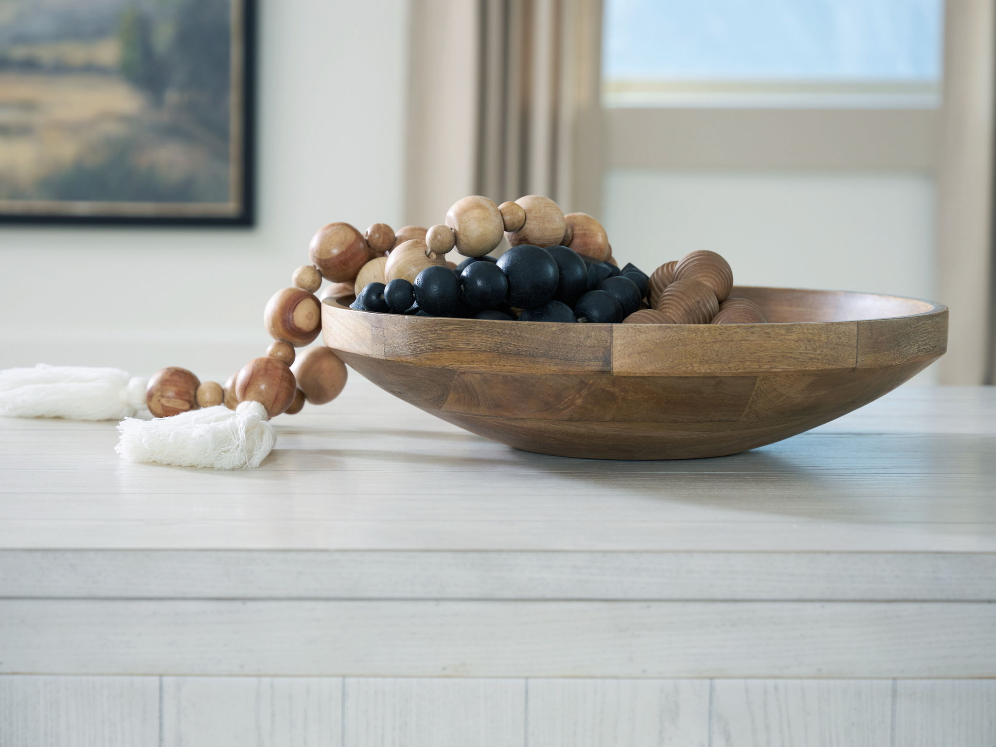 Natural brown wooden bowl on tabletop with mixed beads and decorative cord