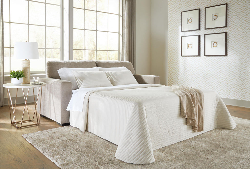 Light gray sofa sleeper with spread white bedding and stacked throw pillows