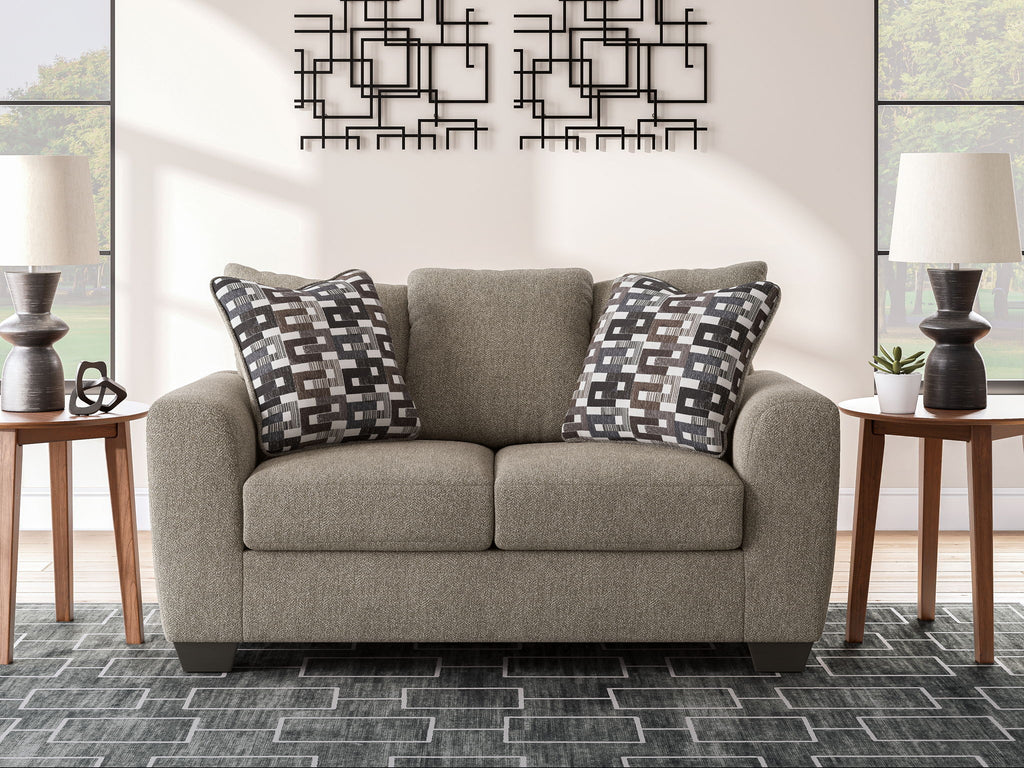 Grey suede loveseat with two patterned throw pillows and two-seat cushions