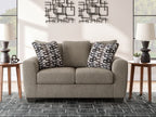 Grey suede loveseat with two patterned throw pillows and two-seat cushions