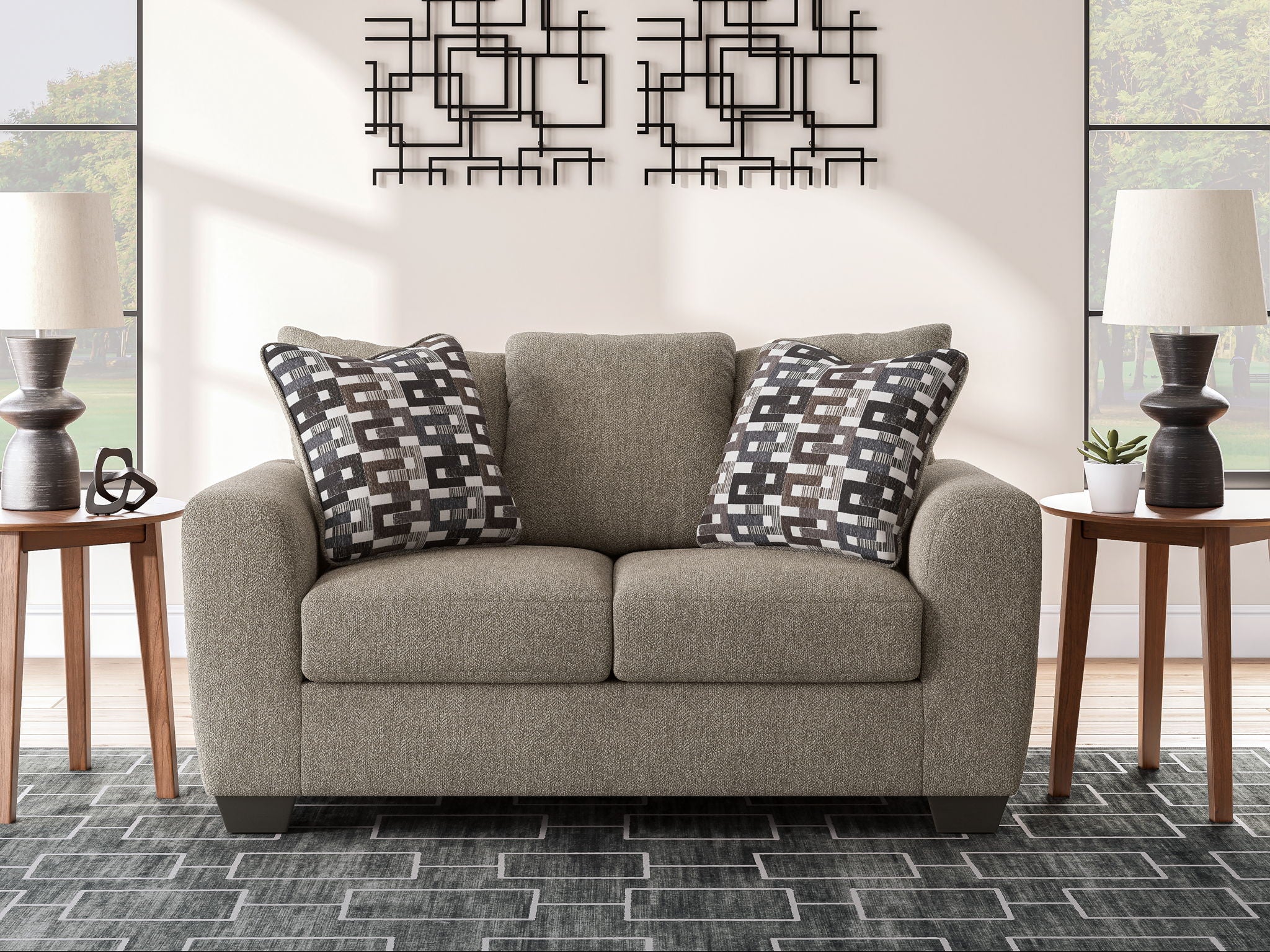 Grey suede loveseat with two patterned throw pillows and two-seat cushions