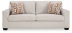 Light beige upholstered sofa with two patterned geometric throw pillows.