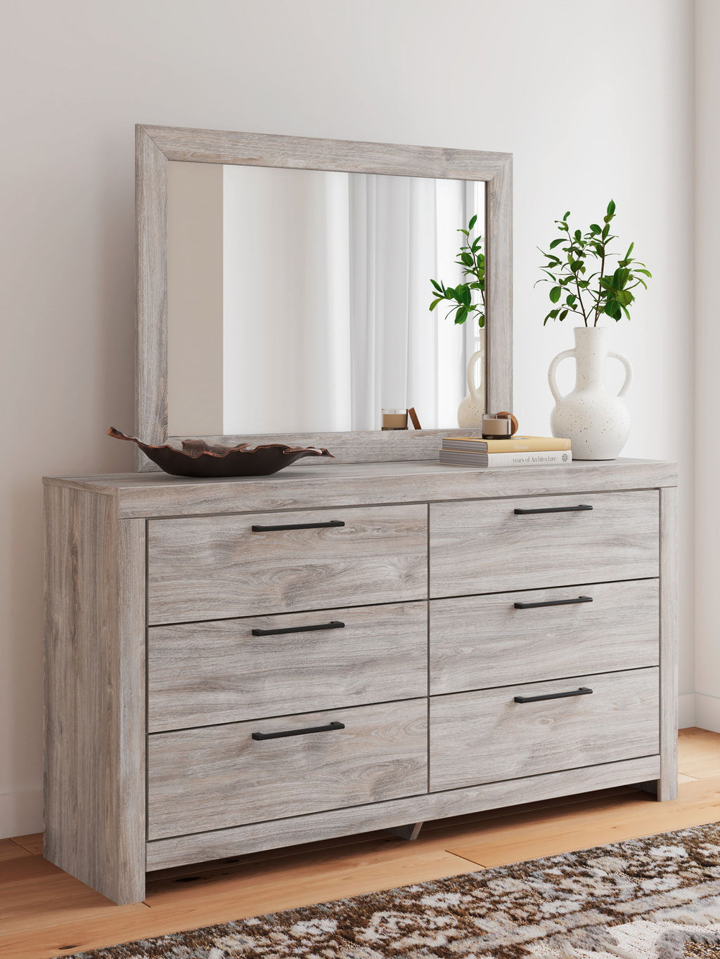 Light gray six-drawer dresser with wall mirror, six drawer fronts with black bar pulls