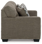 Dark brown loveseat with rounded arm, side view, and patterned throw pillow
