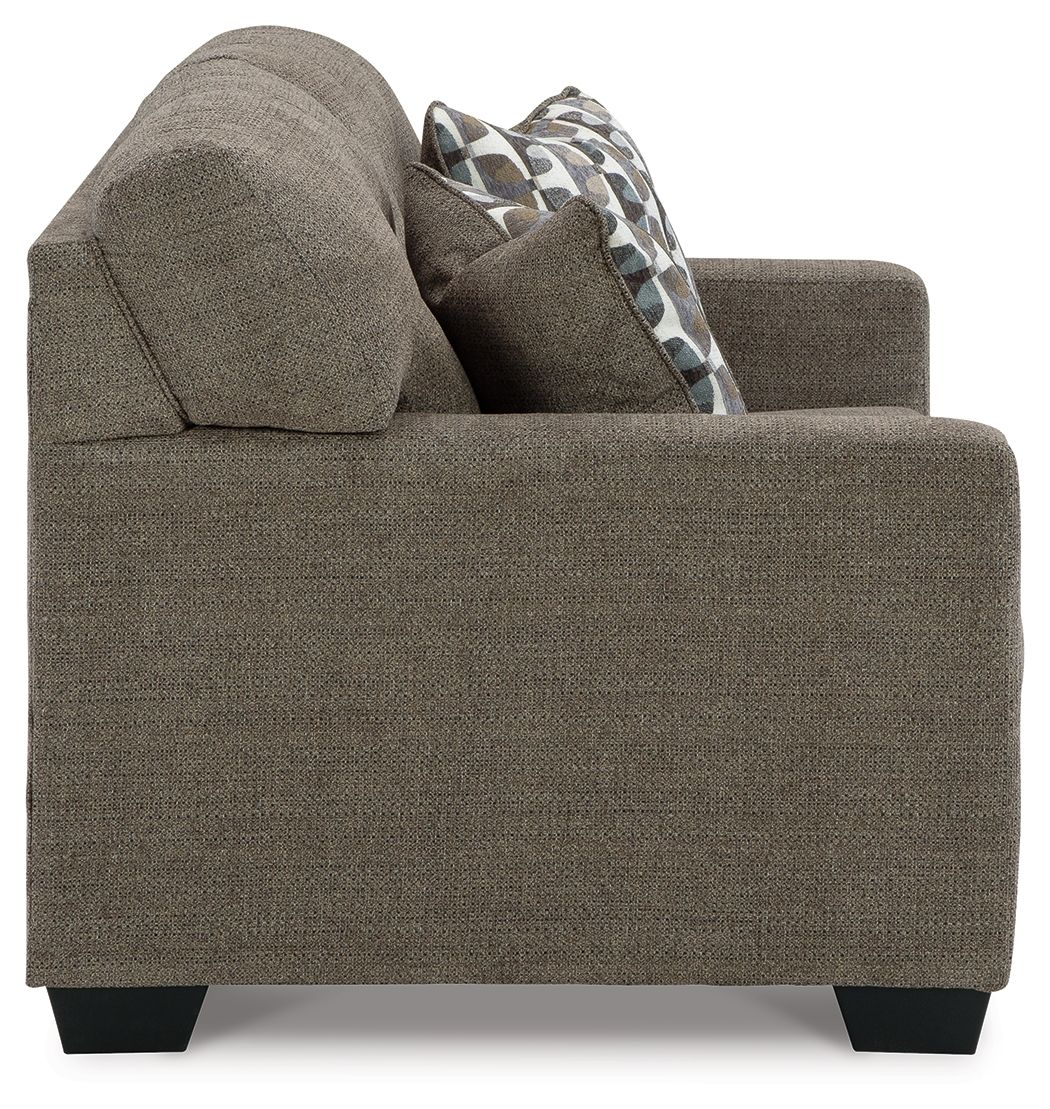 Dark brown loveseat with rounded arm, side view, and patterned throw pillow