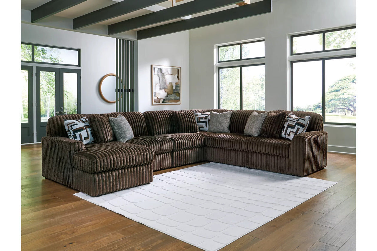 Dark charcoal sectional sofa with corner chaise and striped throw pillows, fabric upholstery.