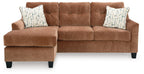 Clay sofa chaise with two square patterned throw pillows and tufted back cushions