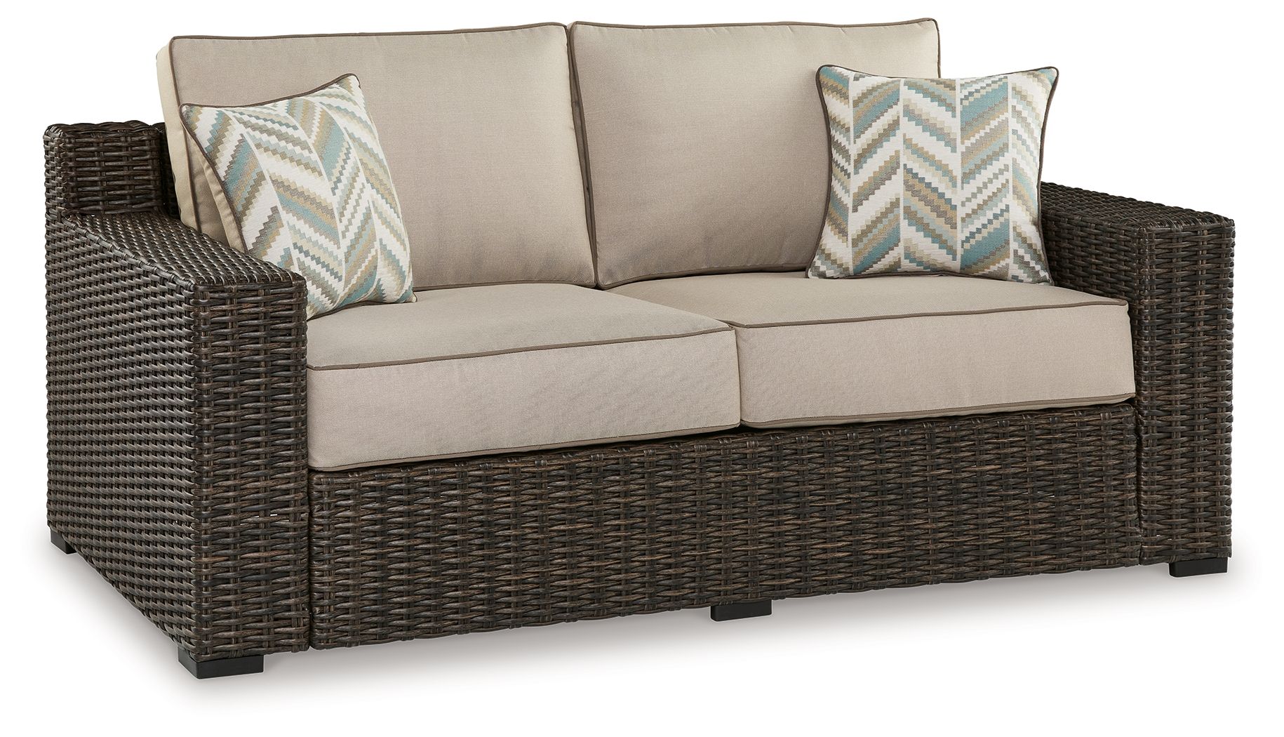 Brown wicker loveseat with beige cushions and two patterned throw pillows