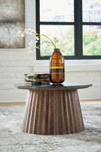 Round black cocktail table with dark stone top and tapered brown wooden legs