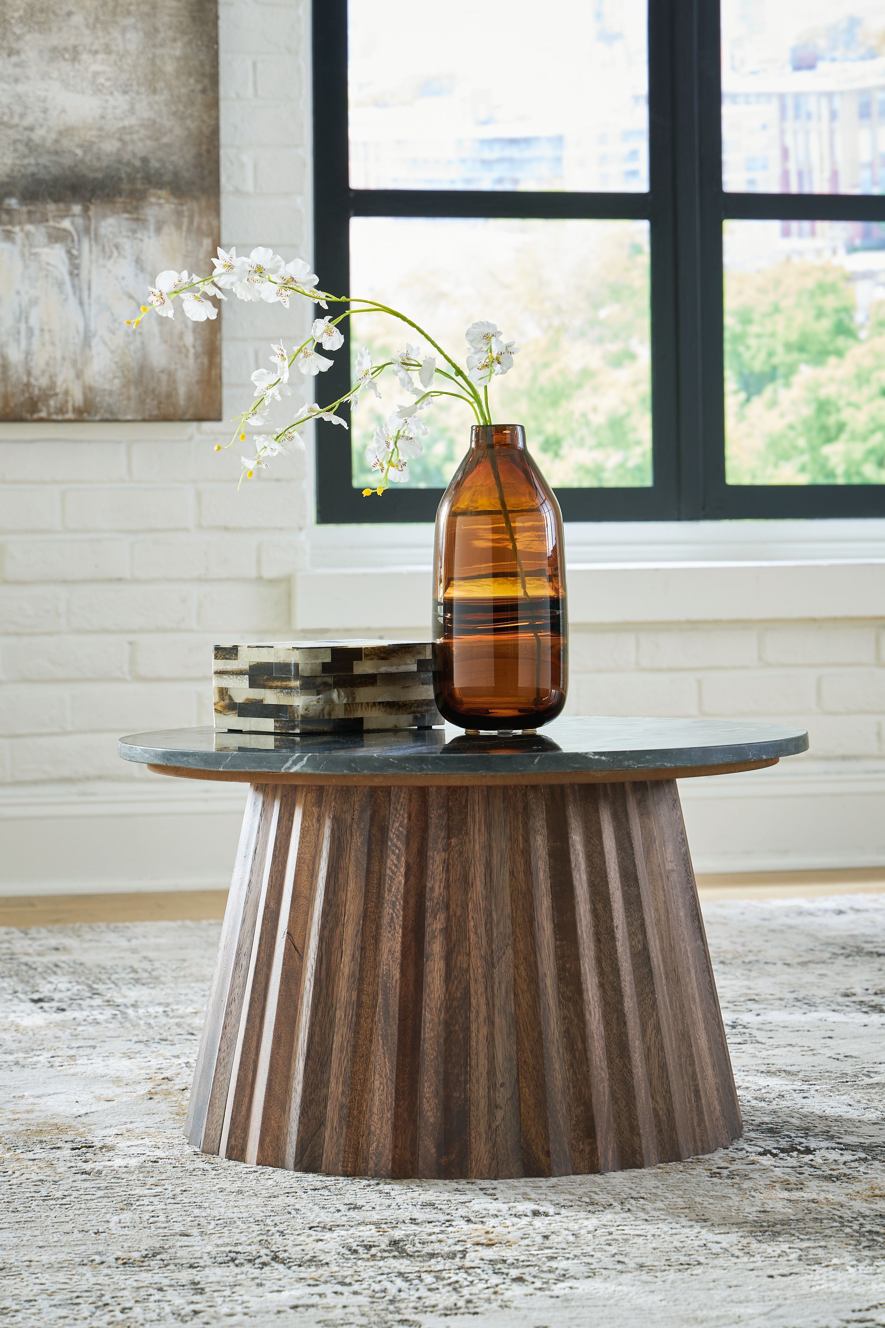 Round black cocktail table with dark stone top and tapered brown wooden legs
