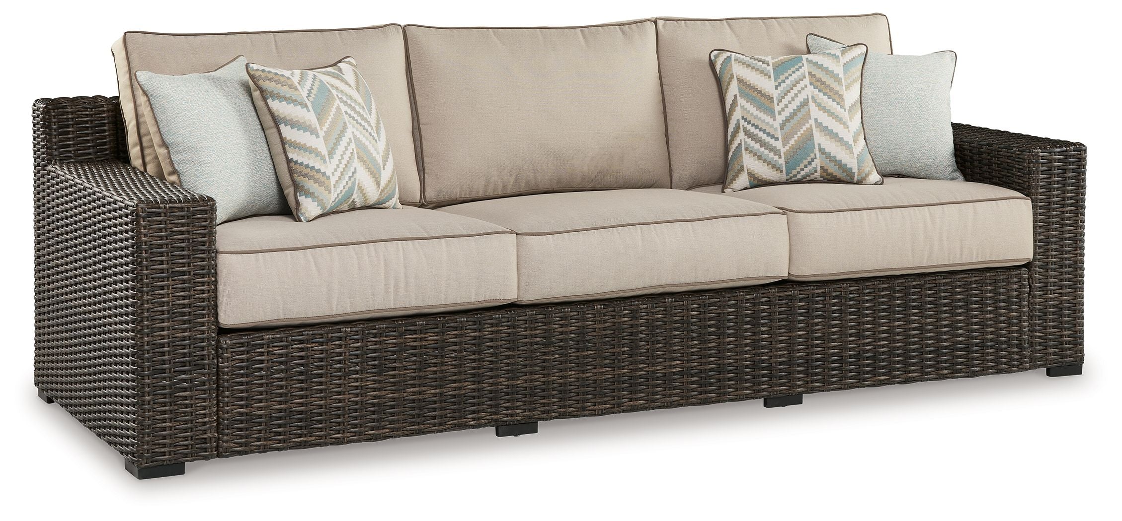 Brown wicker sofa with beige seat cushions and two patterned throw pillows