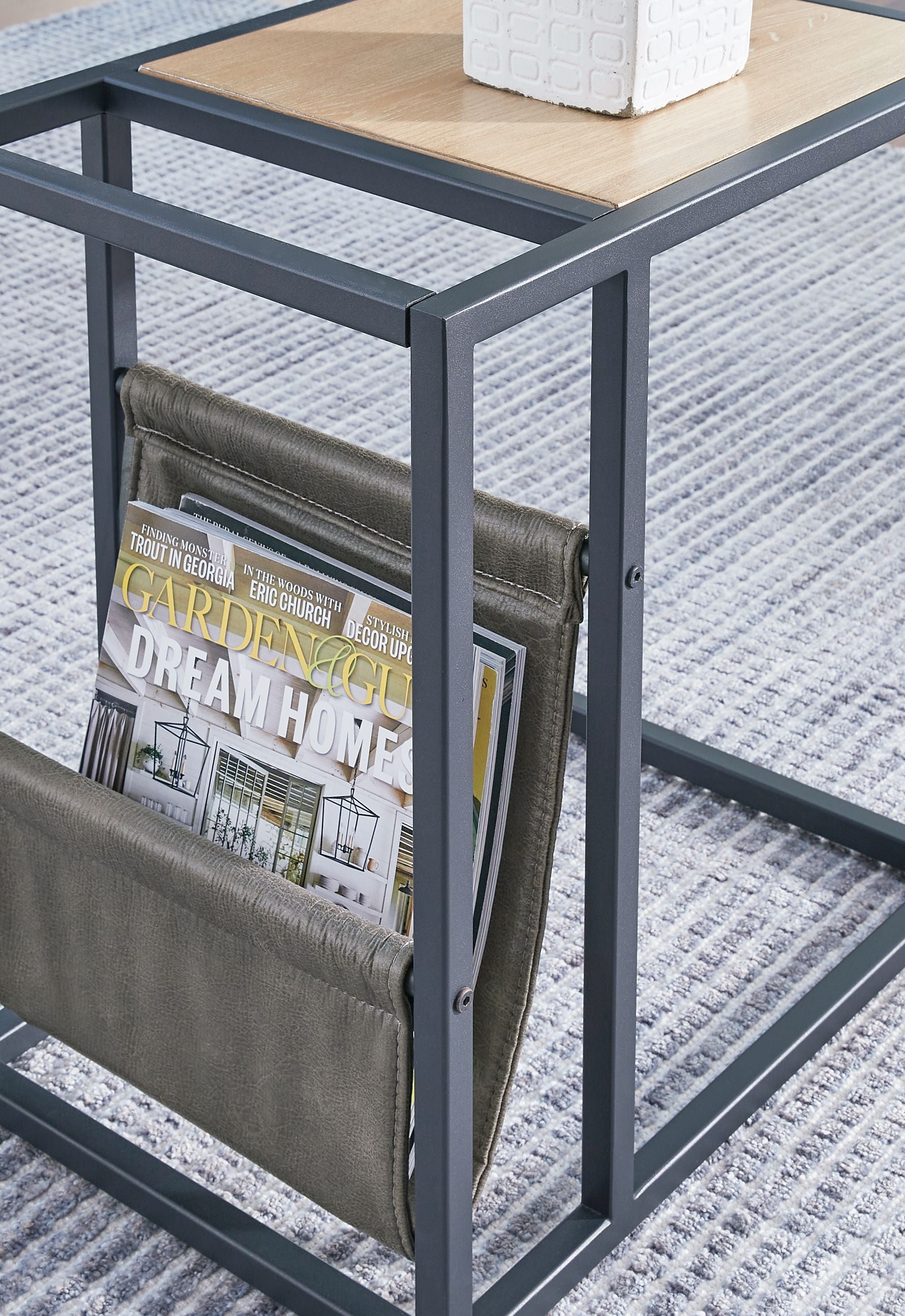 Magazine basket detail on side end table with olive panels and dark frame