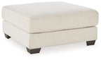 Oversized ottoman with beige fabric upholstery and dark tapered feet.
