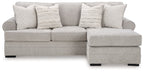 Light gray sofa chaise with wide chaise end, padded armrests, and three patterned throw pillows