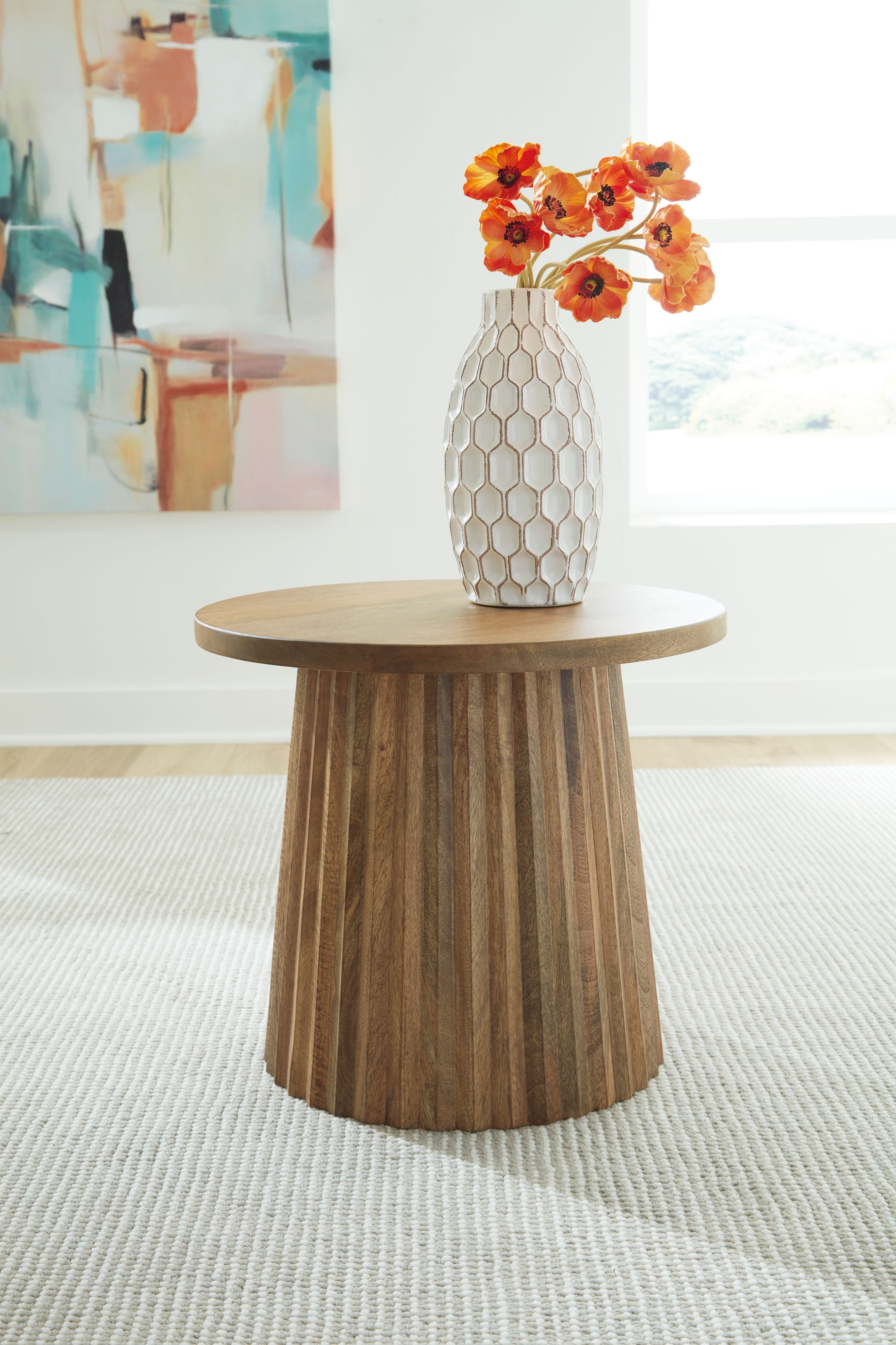 Light brown round accent table with vase on top