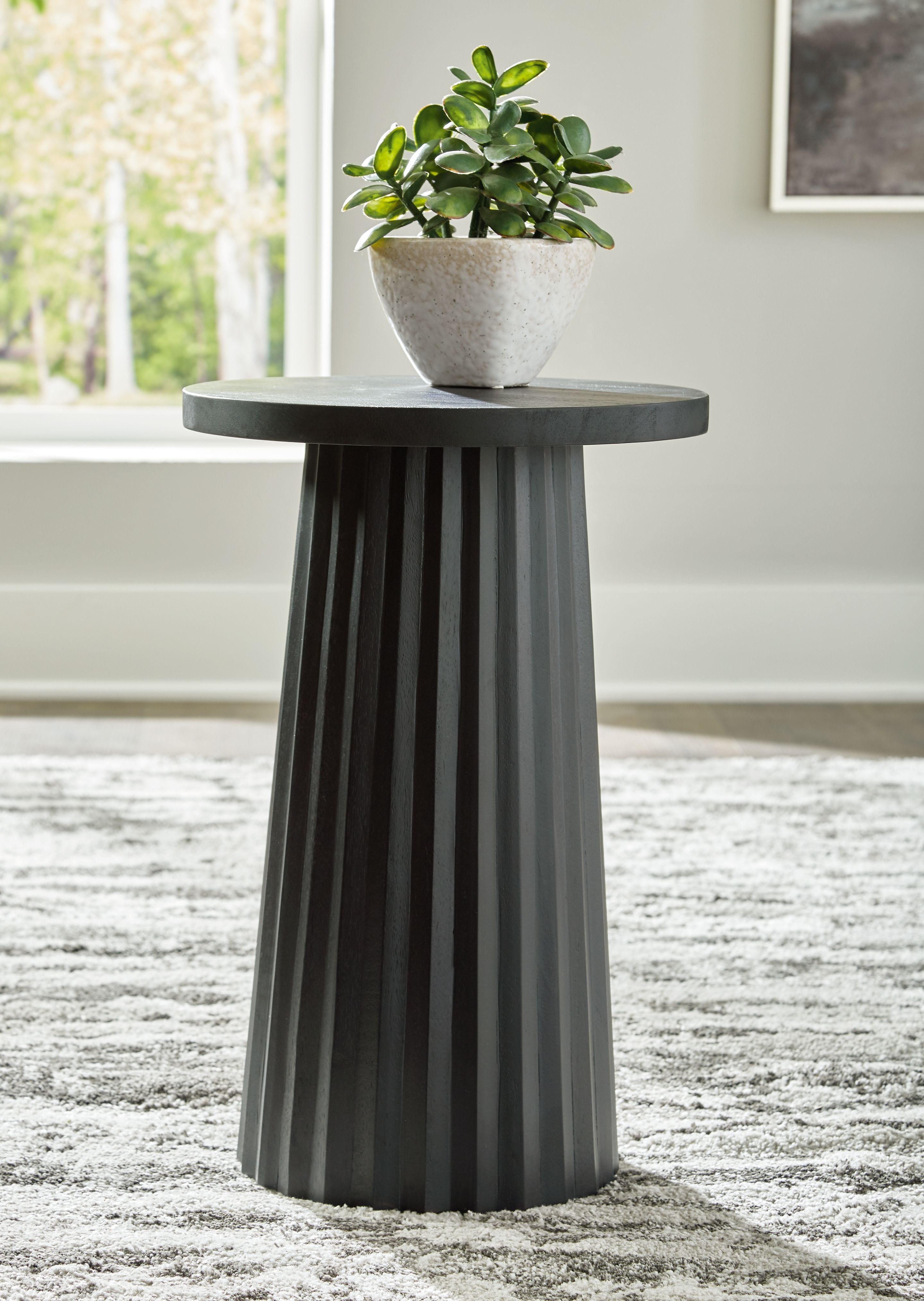 Black round accent table with planter on top