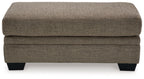 Upholstered ottoman in dark brown fabric with stitched panels and black legs.