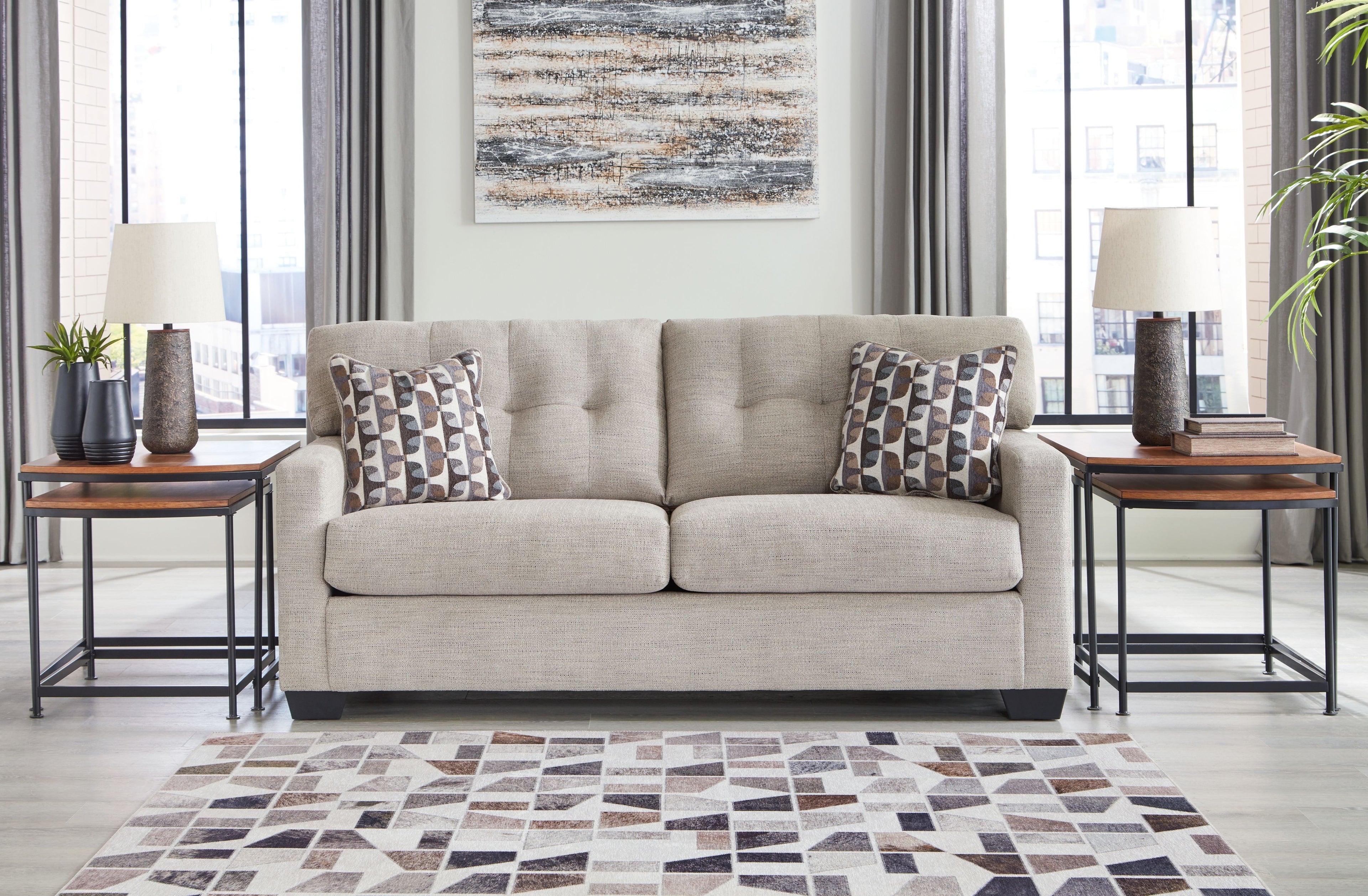 Light gray sofa with two seat cushions and two patterned throw pillows