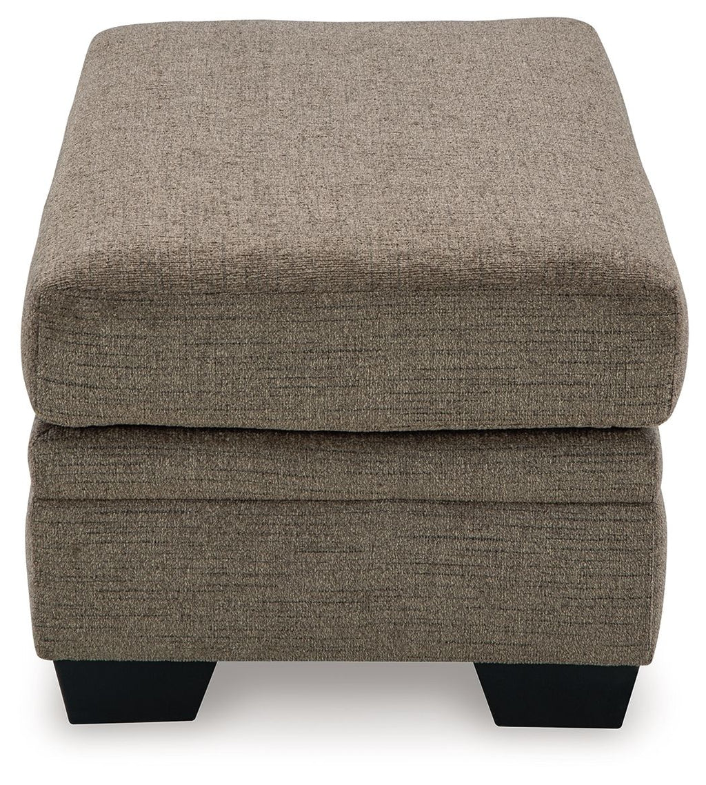 Upholstered ottoman in medium brown fabric with stitched top and black legs.