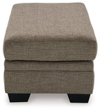 Upholstered ottoman in medium brown fabric with stitched top and black legs.