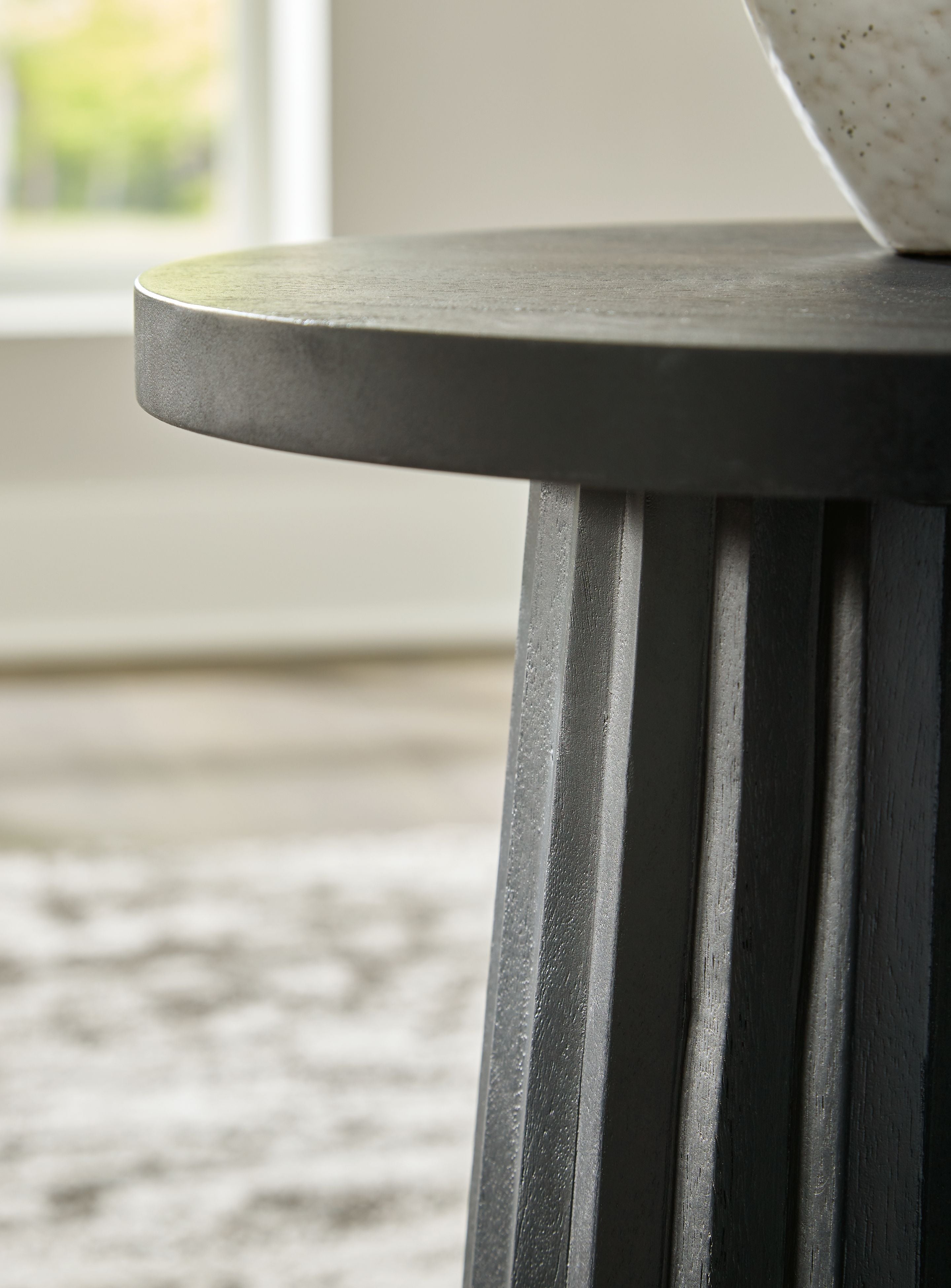 Grey-black fluted pedestal leg under round tabletop