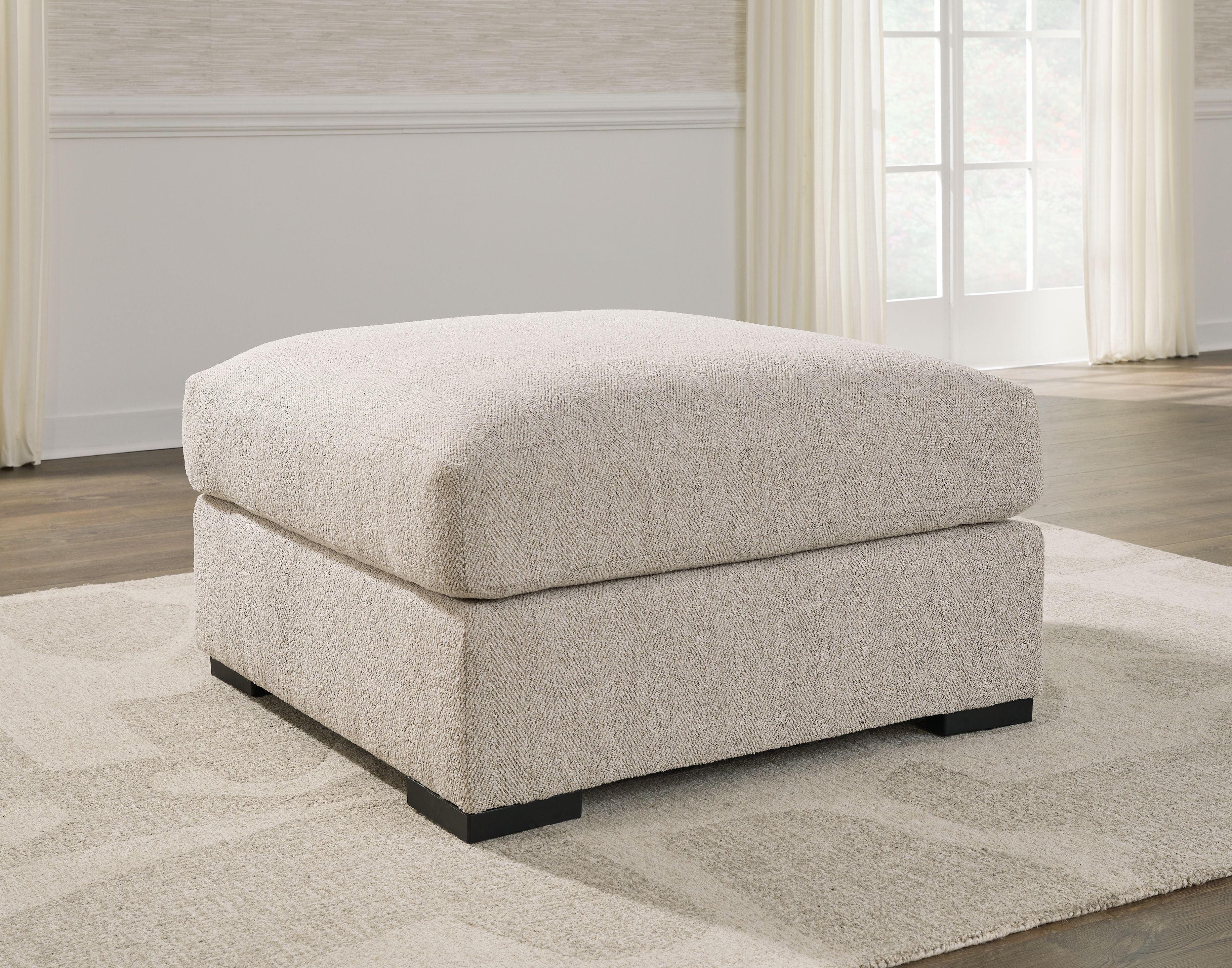 Sand-colored ottoman with rounded padded top and dark block base