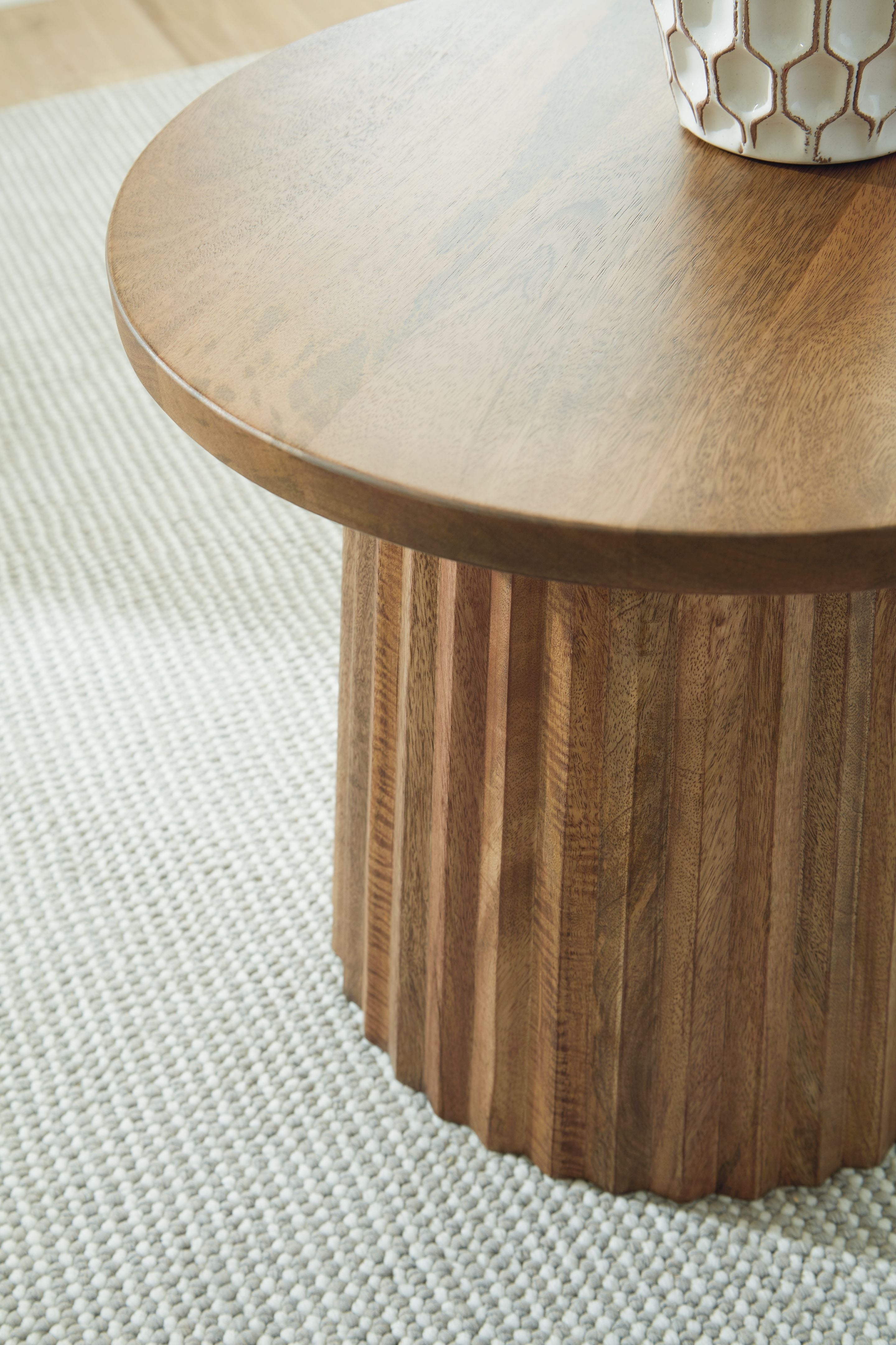 Light brown round accent table with visible wood edge grain